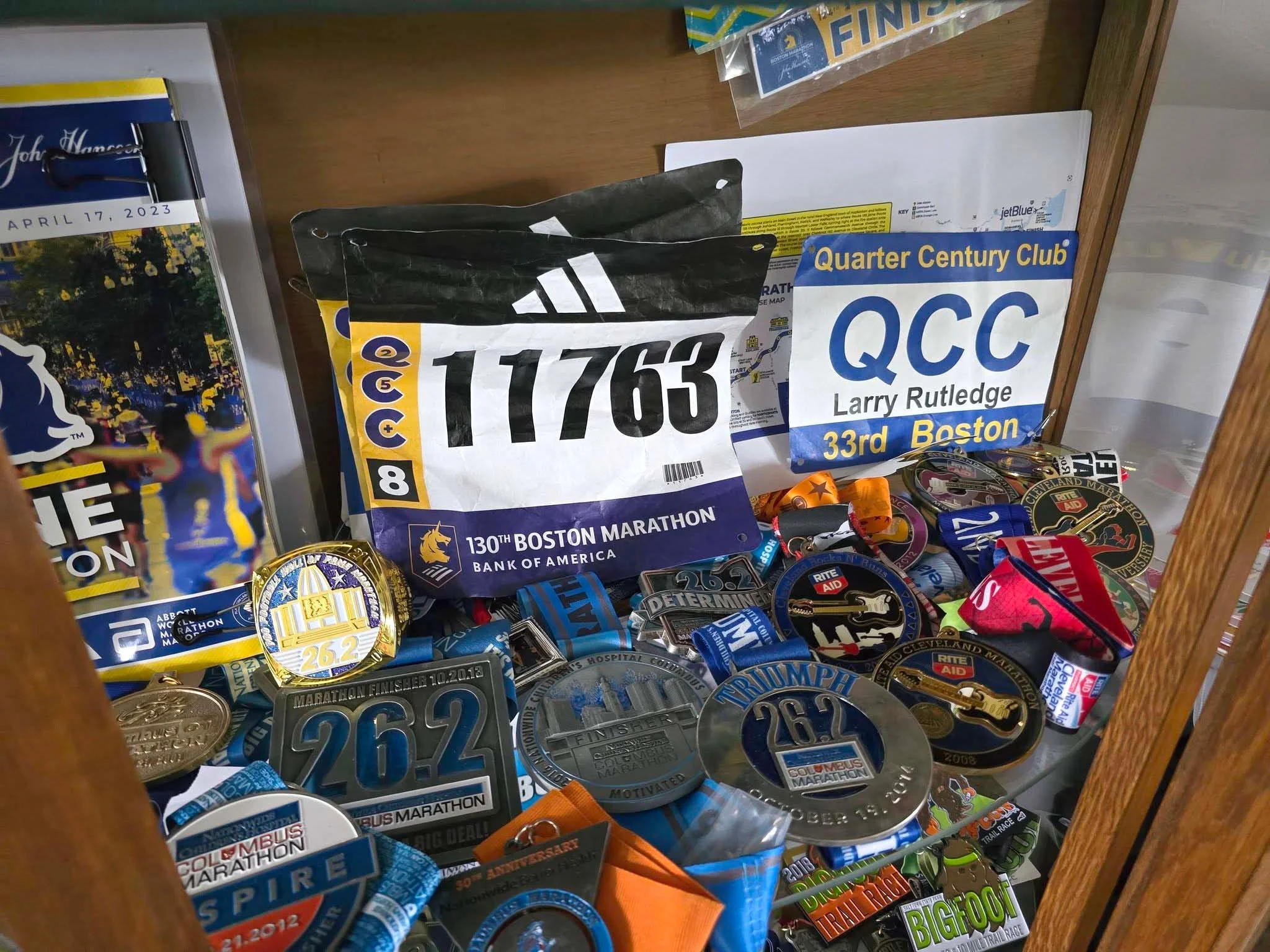 Collection of marathon bibs and medals displayed in a cabinet.