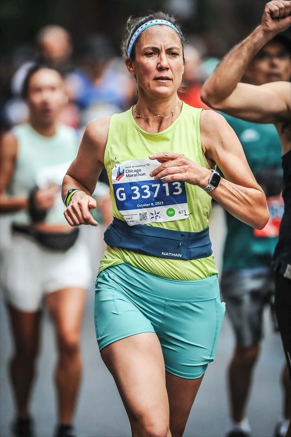 A runner participating in the Chicago Marathon, wearing a green tank top and shorts, focused on the race. A runner participating in the Chicago Marathon, wearing a green tank top and shorts, focused on the race.