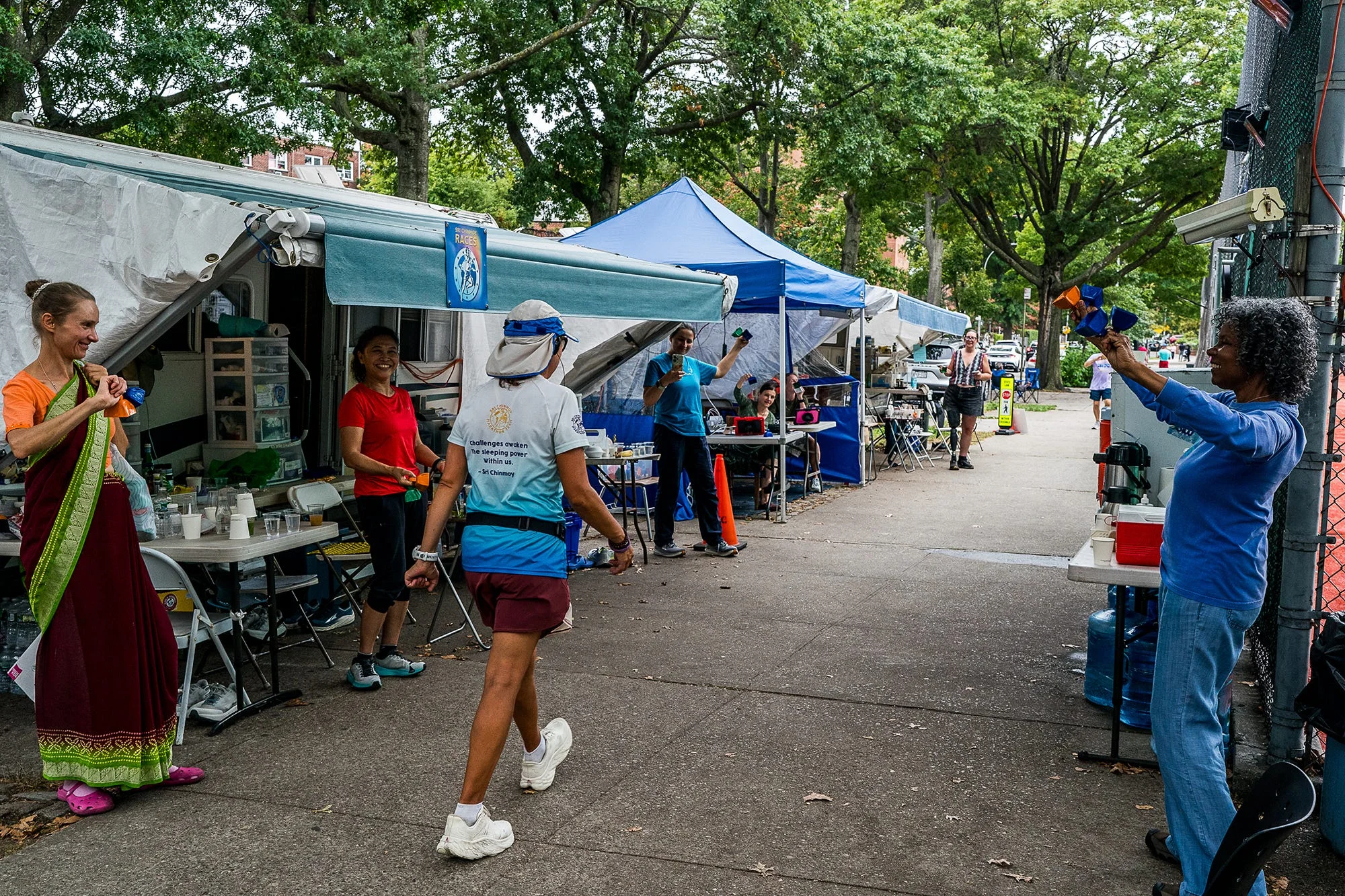 supports ring bells for runners marking the halfway point of the race during the sri chinmoy 3100 mile race in queens, new york on september 24, 2025 the race circles a high school over the corse of 2 months for 3100 miles