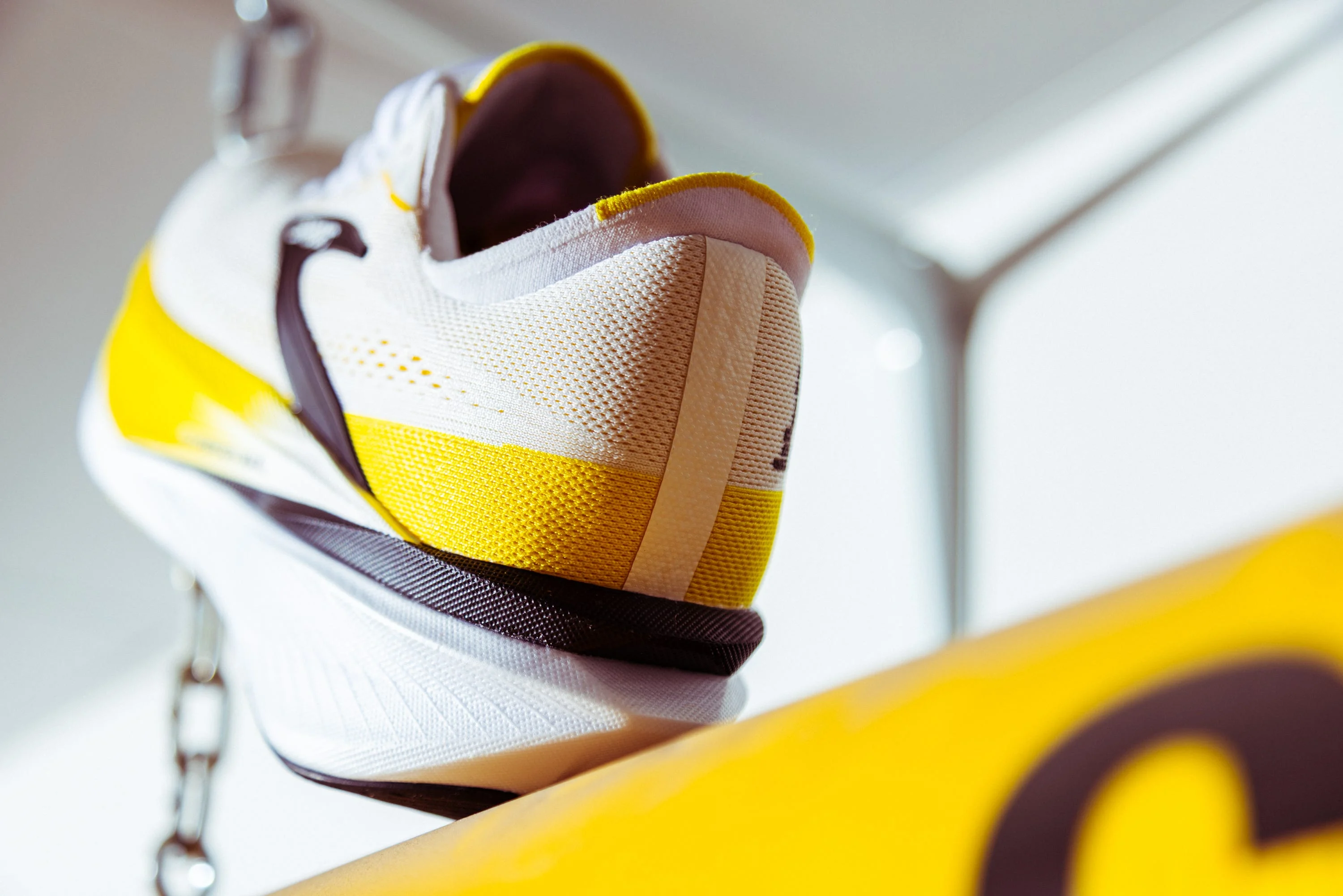 Close-up of a white and yellow athletic shoe with a textured surface. Close-up of a white and yellow athletic shoe with a textured surface.